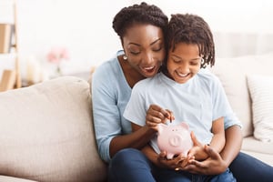 a parent teaches their child ways to be financially responsible with a piggy bank