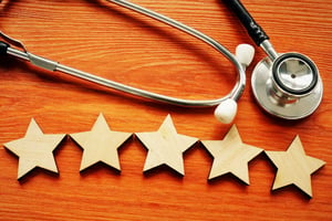 stethoscope lying on professional wooden desk above five golden stars symbolizing patient satisfaction and retention
