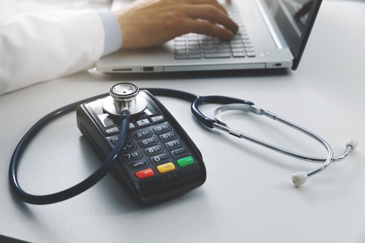 close up of doctor's stethoscope and hand as he types on a laptop and determines what are my payment options for addiction treatment